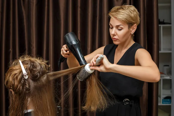 utilisation du sèche-cheveux par une coiffeuse professionnelle de la coiffure